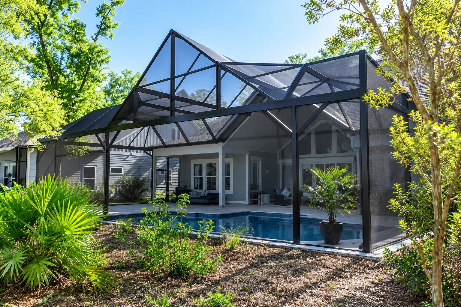 Screened patio enclosure with a black peaked frame around a backyard pool and patio.