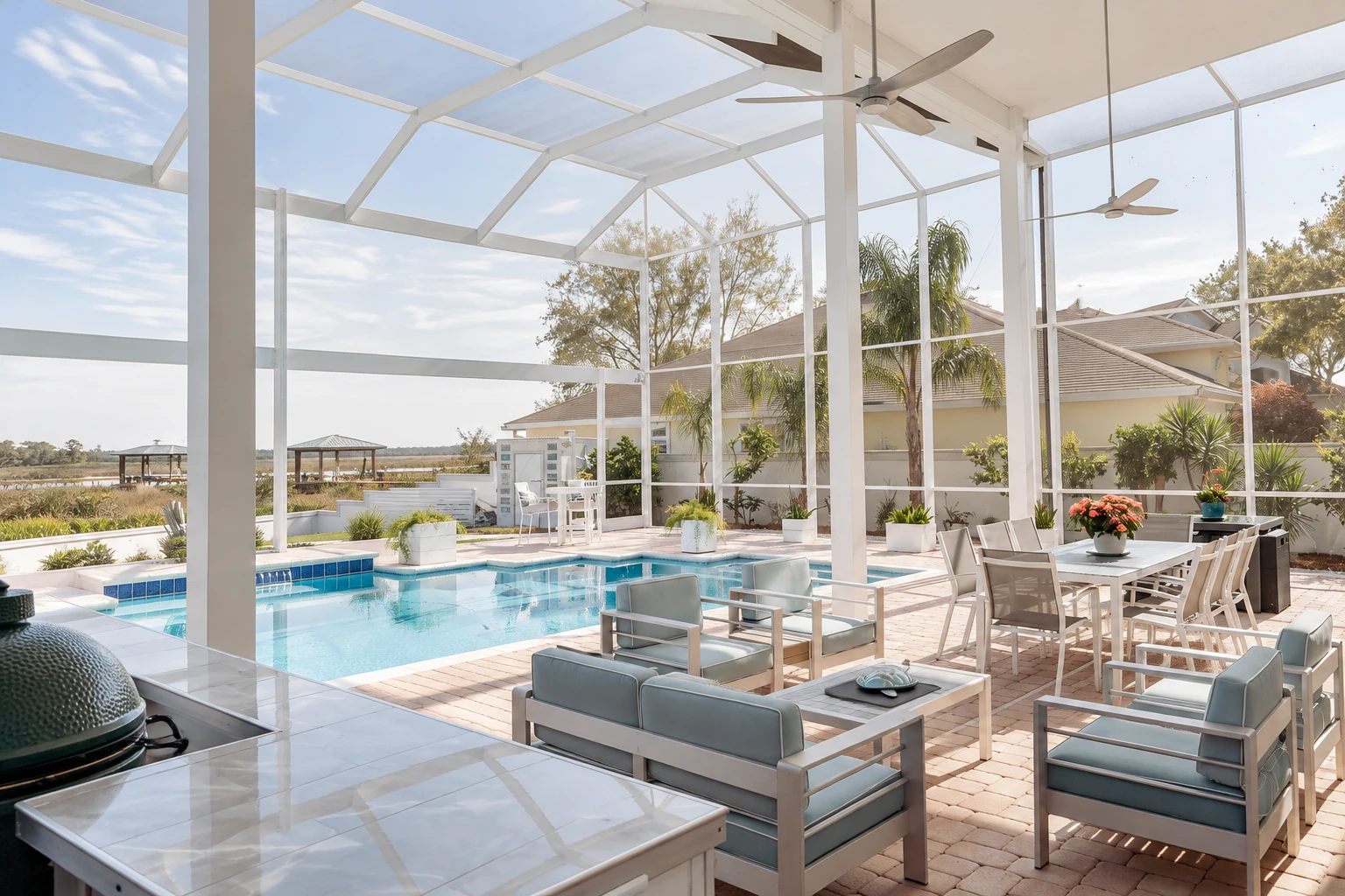 Spacious glass-enclosed patio with a swimming pool, white framing, ceiling fans, and outdoor dining and lounge furniture.